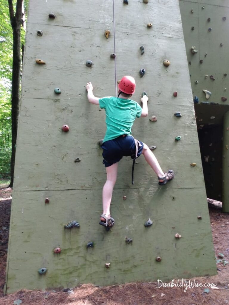 teen boy scaling a rock wall in the summer 