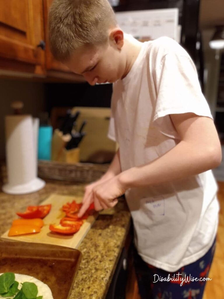 teen cutting vegetables in a kitchen working on daily living skills