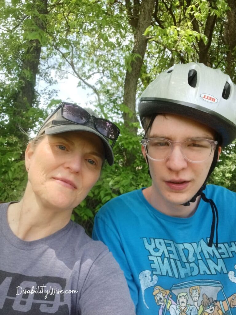 mother and teen son with bike helmet on sitting outside during the summer 