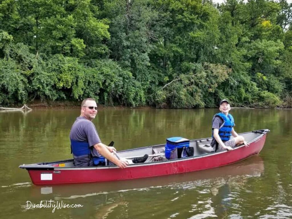 Dad and son with disability in a red canoe on the water 