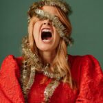 woman in red dress with garland around head stressed over the holidays