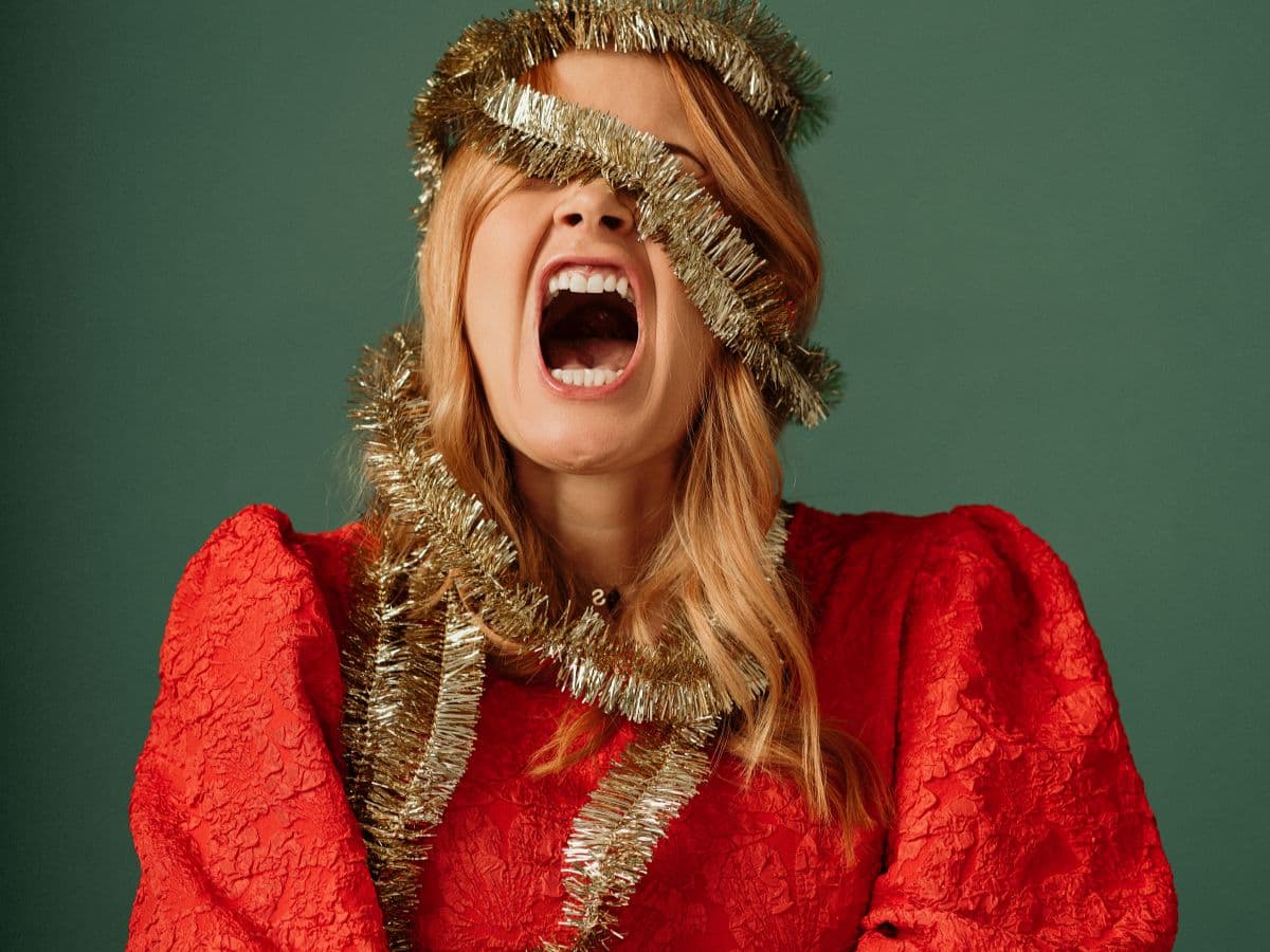 woman in red dress with garland around head stressed over the holidays