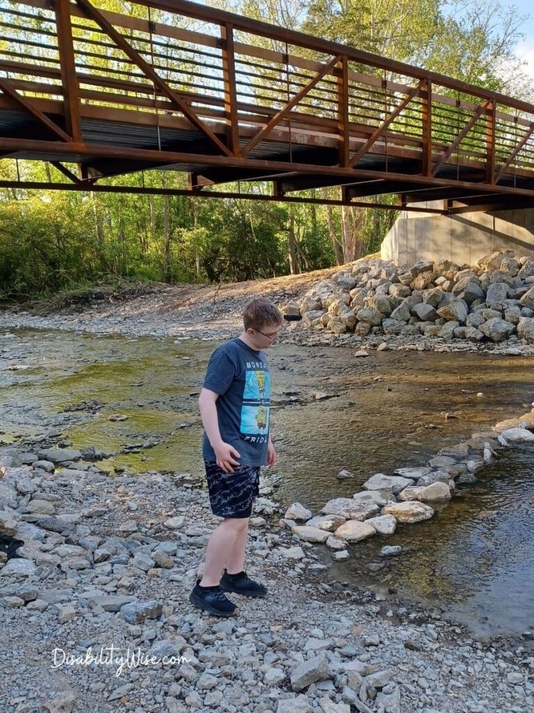 teen boy at a creek near a bridge 