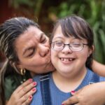 Mom kissing her teen daughter with developmental disabilities