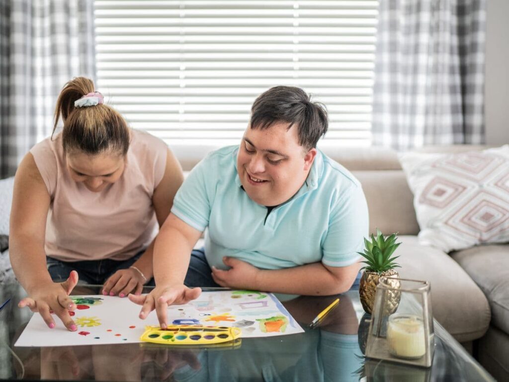 Two adults with developmental disabilities finger painting 