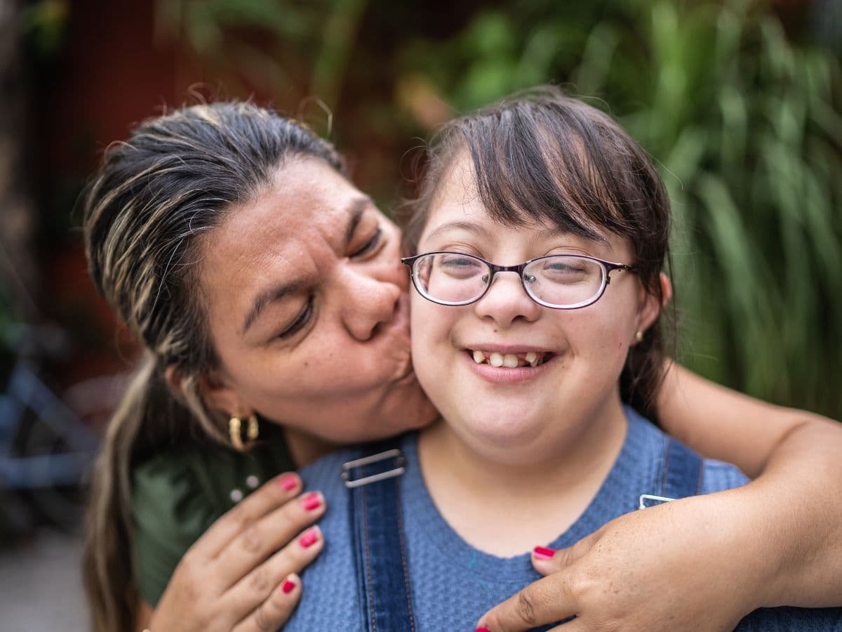Mom kissing her teen daughter with developmental disabilities