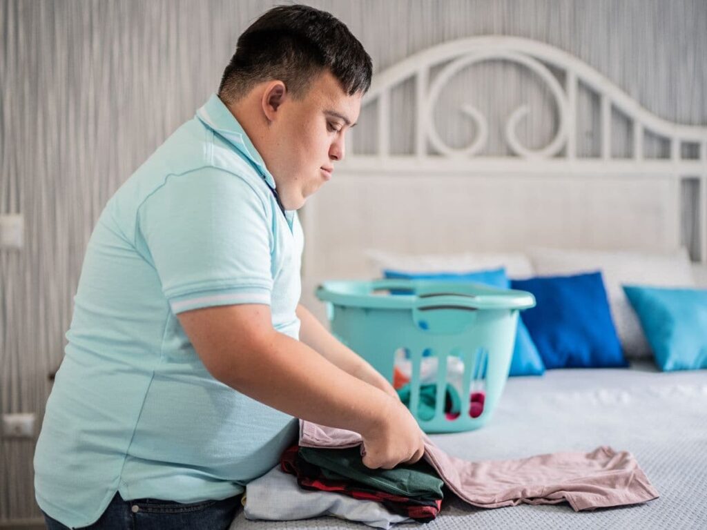 adult with developmental disabilities folding clothes on a bed