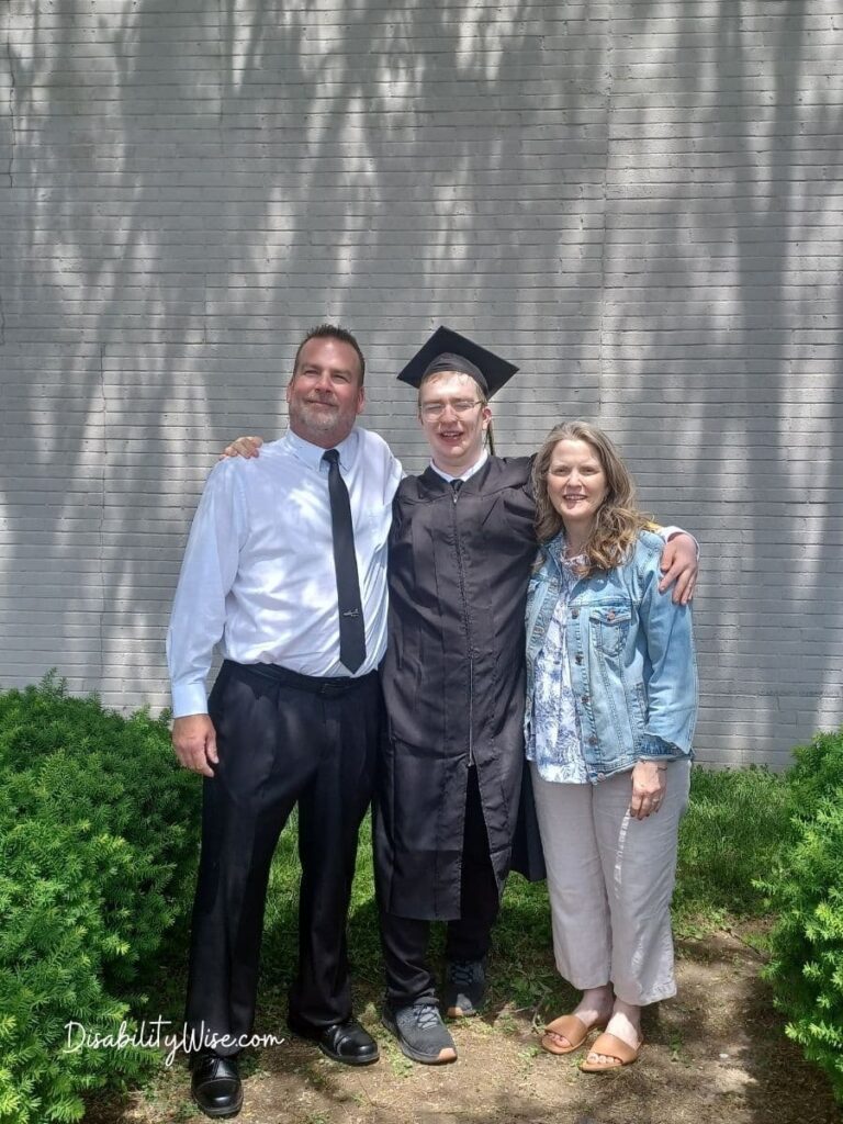 teen with developmental disability in cap and gown with parents